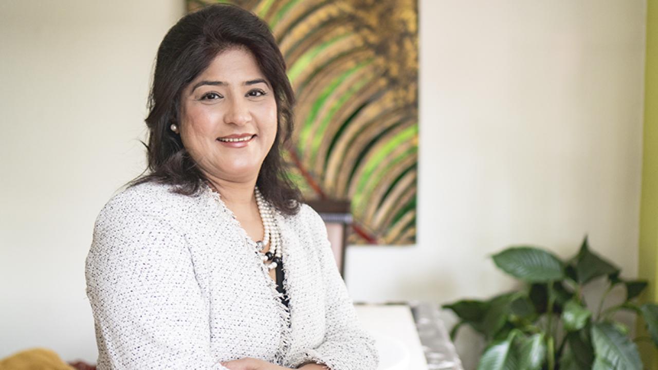 Photo of Ekta Vyas smiling at camera, standing with arms folded across chest