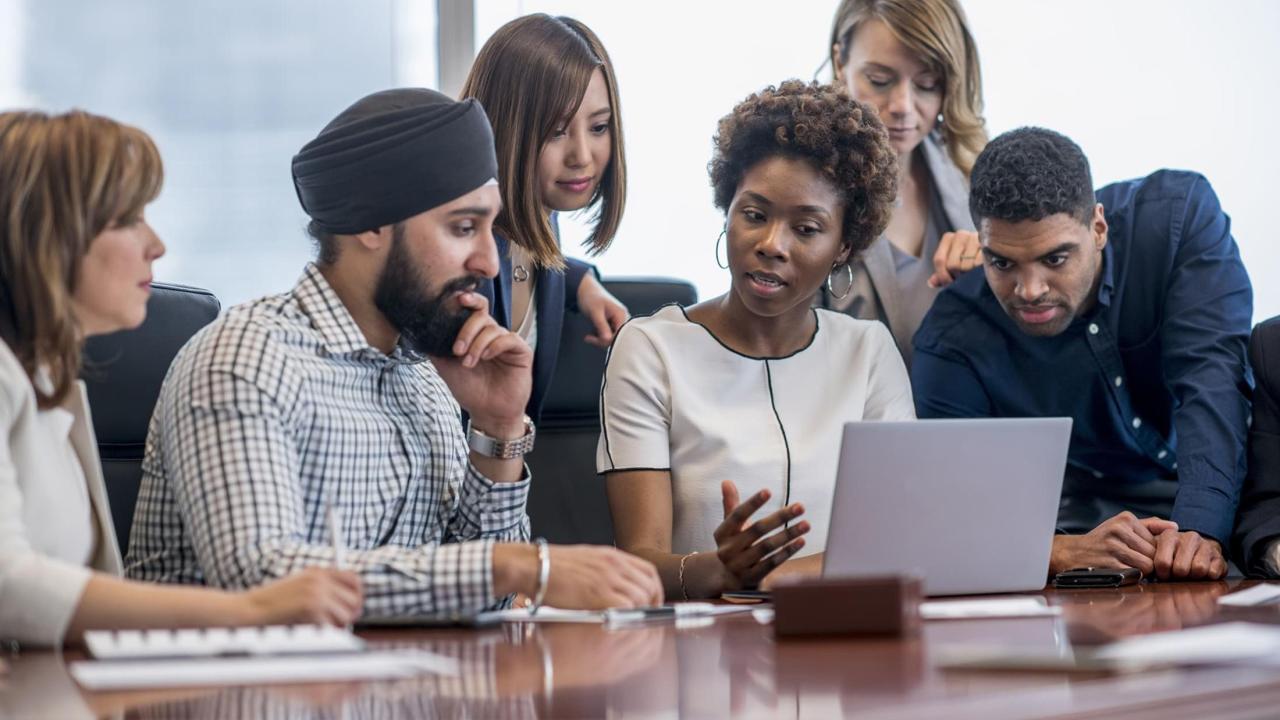 Diverse group of employees sit around a table.