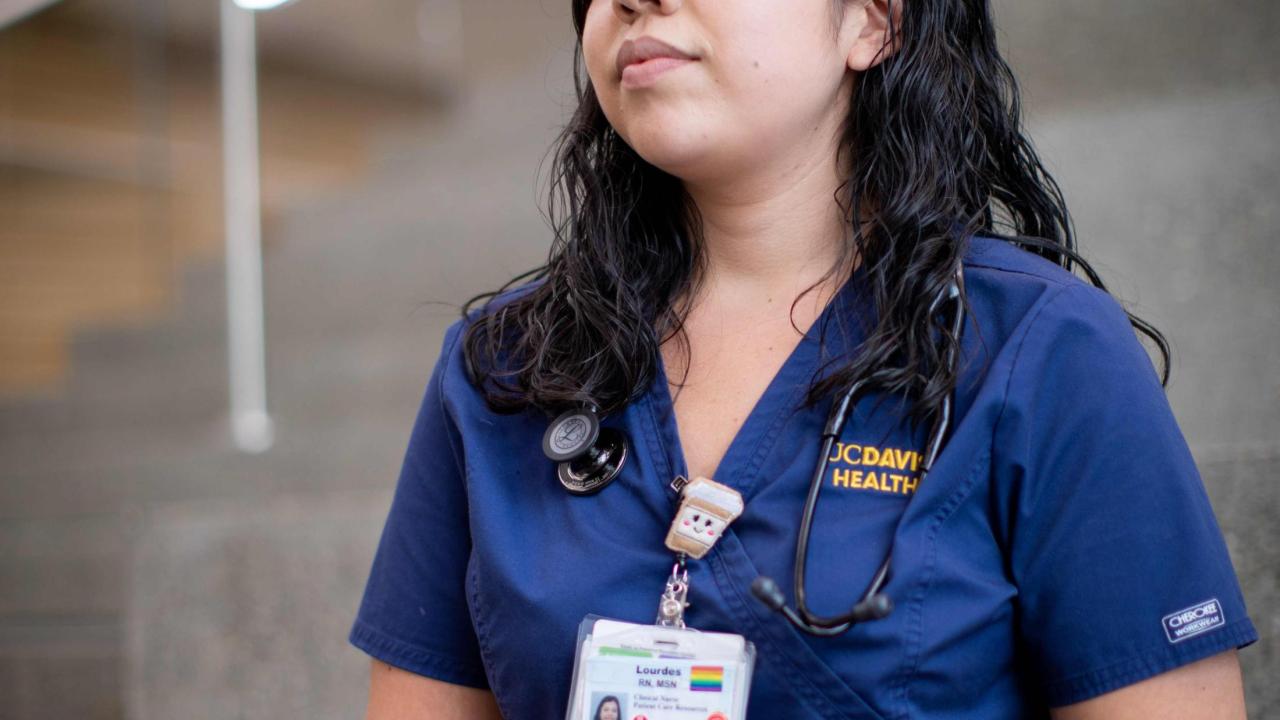 Nurse is sitting, looking off into the distance.  She looks as if she is contemplating something.  