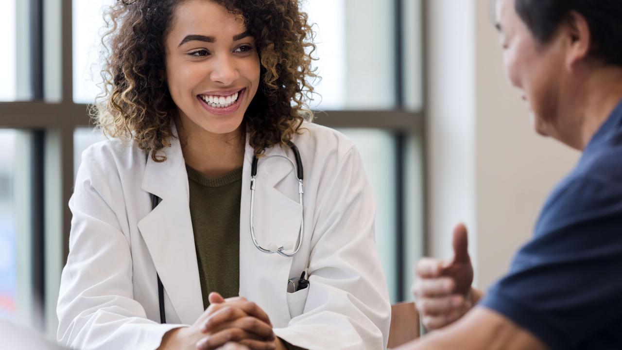 Female doctor smiling at male patient while having a conversation.
