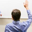 man holding up his hand to ask a question of an instructor